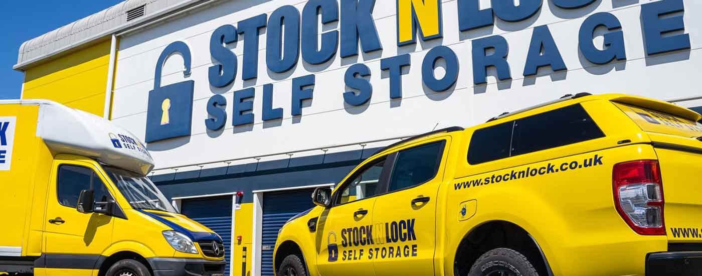Stock N Lock Self Storage facility with branded yellow van and pickup truck parked in front of the building