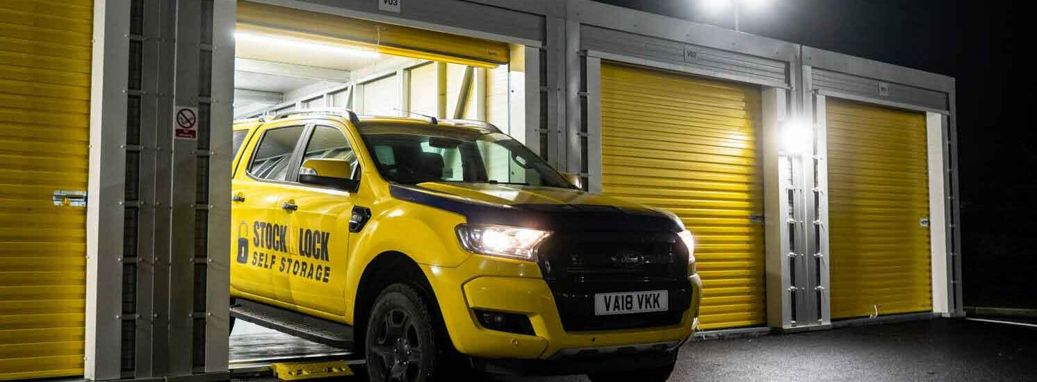 Yellow Stock N Lock Self Storage truck parked outside storage units at night