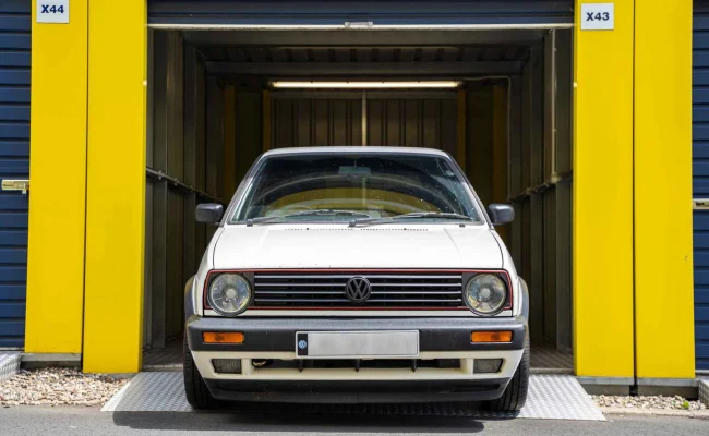 White Volkswagen parked inside a yellow self-storage unit