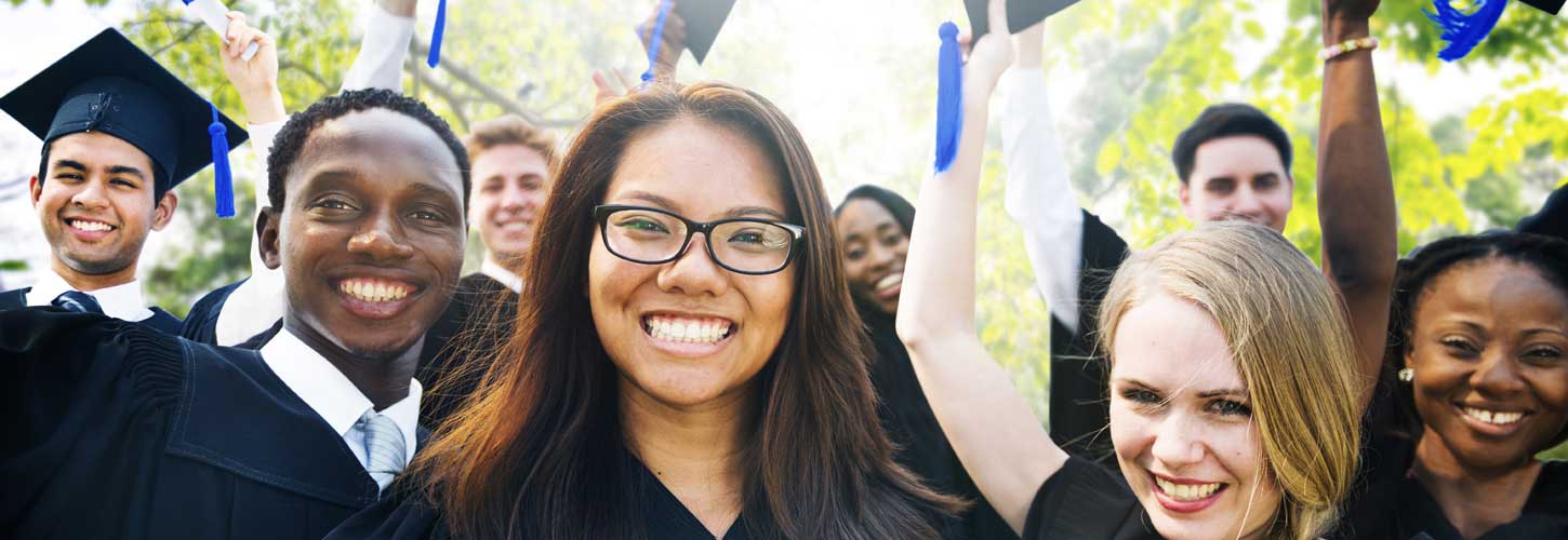 Diverse group of smiling students celebrating graduation in caps and gowns